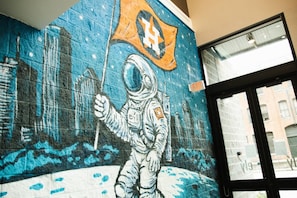A mural of an astronaut with a flag, a window, and an exit sign. - Downtown Houston Skyline Stay, Steps to Daikin Park D (Houston)