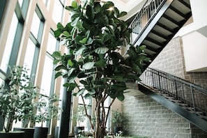 A multi-level indoor space with a staircase, large windows, and various indoor plants. - Downtown Houston Skyline Stay, Steps to Daikin Park D (Houston)