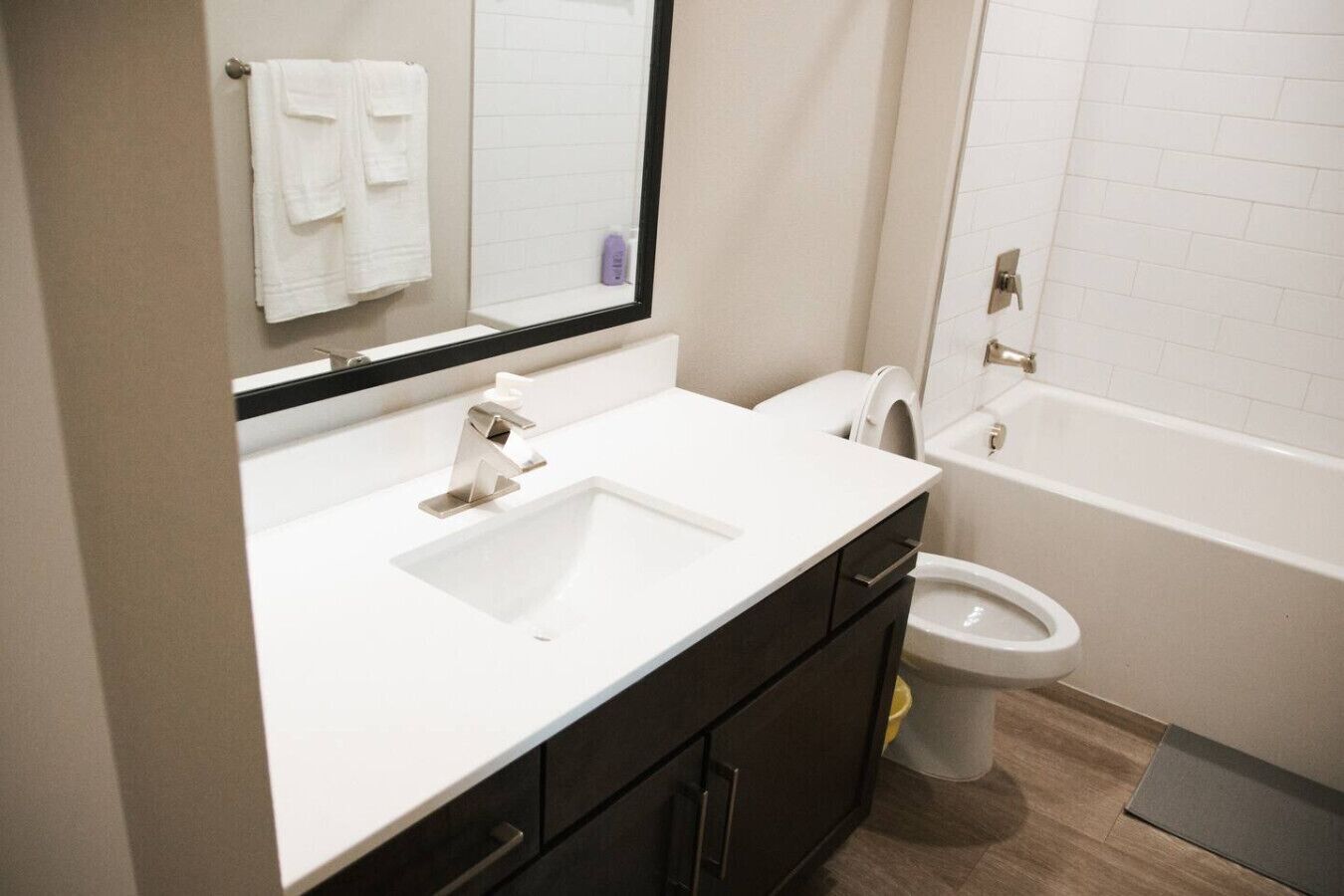 Ein Badezimmer mit einem weißen Waschbecken, dunklen Schränken, einer Toilette und einer Badewanne.