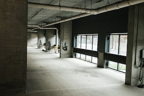 A spacious indoor area with concrete pillars, large windows, and visible electrical outlets on the walls. - Downtown Houston Skyline Stay, Steps to Daikin Park G (Houston)
