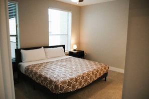 A bedroom with a bed, a nightstand, a lamp, and a window with blinds. - Downtown Houston Skyline Stay, Steps to Daikin Park G (Houston)