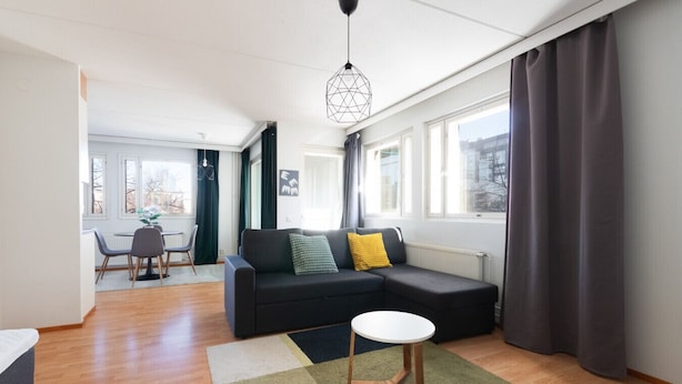 Ein modernes Wohnzimmer mit einer Eckcouch, einem runden Couchtisch und einem Essbereich mit Stühlen und Tisch.