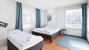 Ein modernes Hotelzimmer mit zwei Betten, einem Heizkörper, einem kleinen Tisch und Blick auf die Stadt.