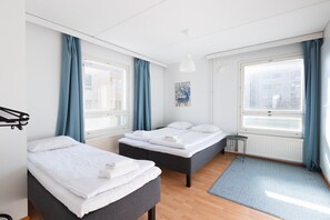 Ett modernt hotellrum med två sängar, ett element, ett litet bord och utsikt över staden.