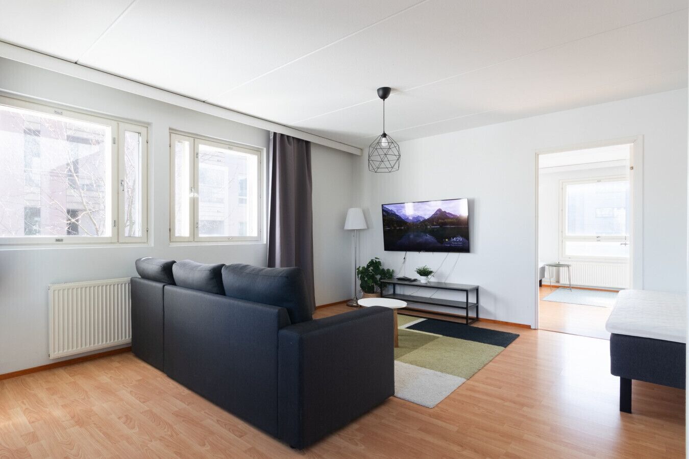 A modern living room with a sofa, a TV, and a dining area.
