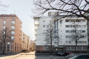 En flervåningsbyggnad med bostäder, kännetecknad av en slät fasad, stora fönster och en parkeringsplats framför.