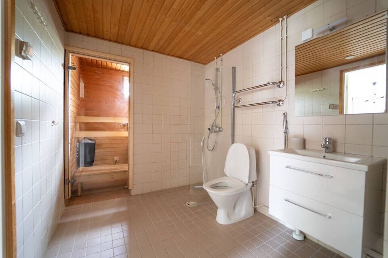 A bathroom with a wooden ceiling, a white toilet, a shower, and a vanity with a mirror.