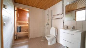 A bathroom with a wooden ceiling, a white toilet, a shower, and a vanity with a mirror.