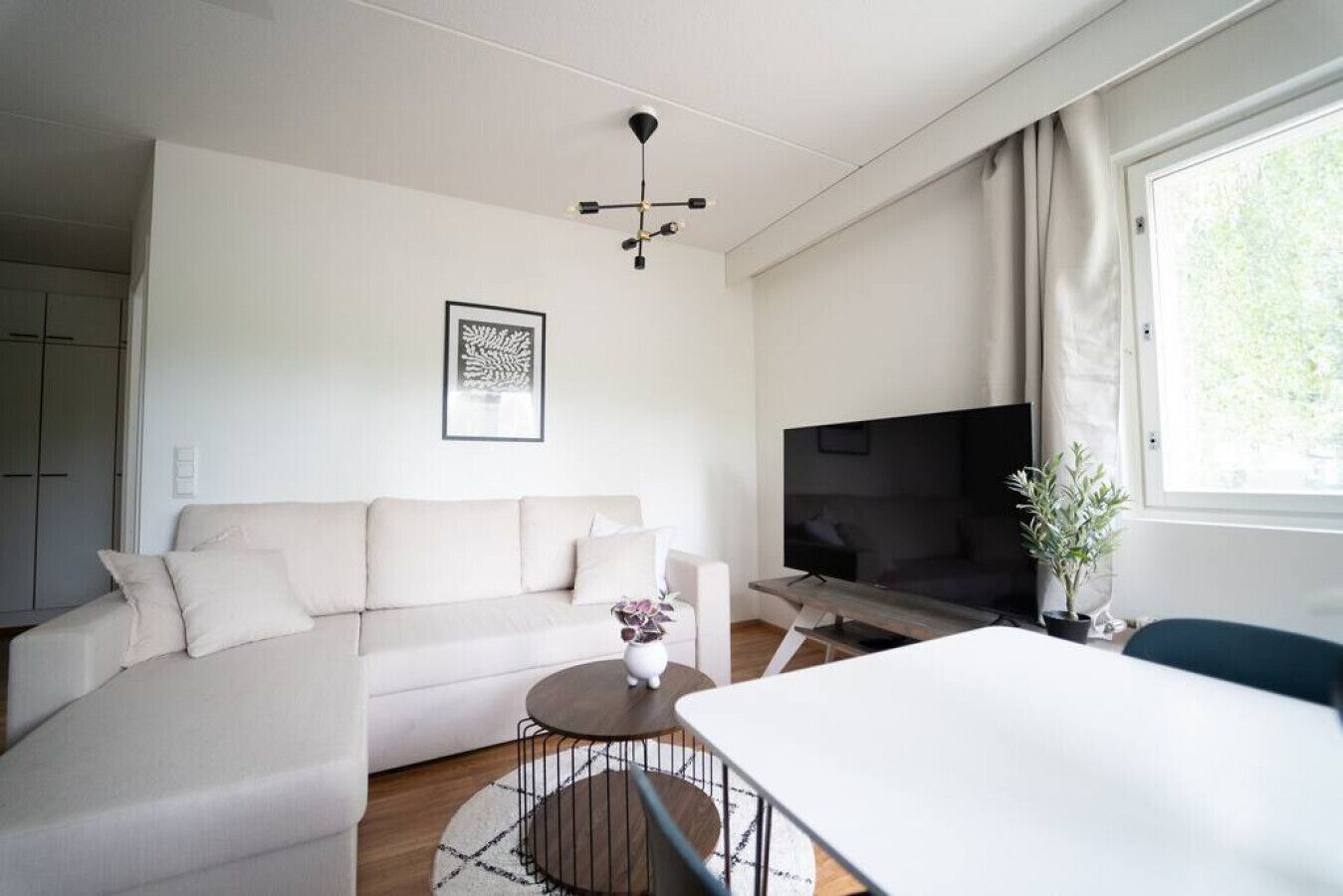 A modern living room with a sofa, a coffee table, a TV, and a dining area.