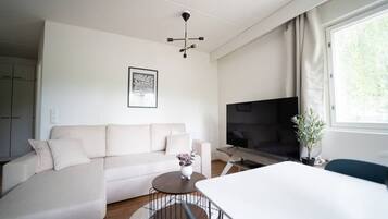 A modern living room with a sofa, a coffee table, a TV, and a dining area.