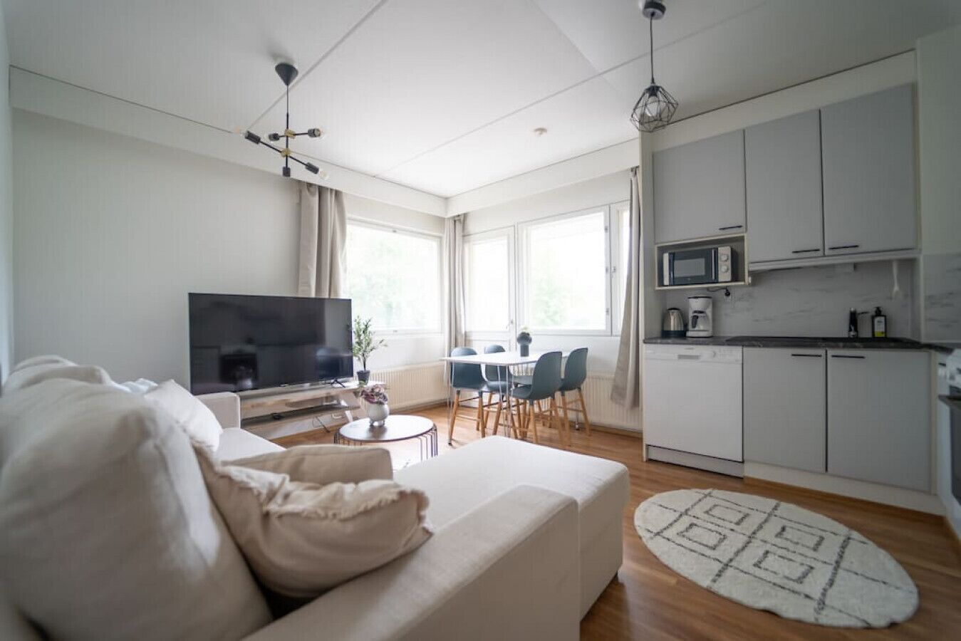 Una sala de estar moderna con un sofá, un televisor de pantalla plana y un comedor con sillas y una mesa.