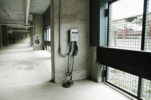 A corridor with a concrete floor, a wall-mounted electrical box, and a window with a metal grid. - Downtown Houston Skyline Stay, Steps to Daikin Park H (Houston)