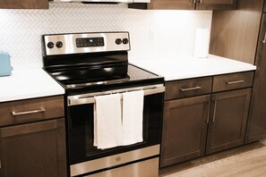 A kitchen with a stainless steel oven, a white countertop, wooden cabinets, and a tiled backsplash. - Downtown Houston Skyline Stay, Steps to Daikin Park H (Houston)