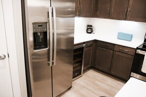 A kitchen with stainless steel appliances, wooden cabinets, a coffee maker, and a blue cutting board. - Downtown Houston Skyline Stay, Steps to Daikin Park H (Houston)