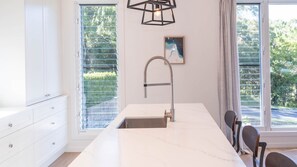 A modern kitchen with a large island, a stainless steel sink, and a pendant light. - Paradise Lights 1770 (Seventeen Seventy)