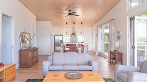 A spacious living area with a sofa, a coffee table, and a dining table. - Paradise Lights 1770 (Seventeen Seventy)