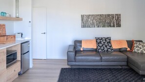 A modern living room with a grey leather sofa, a black patterned rug, and a minimalist decor. - Paradise Lights 1770 (Seventeen Seventy)