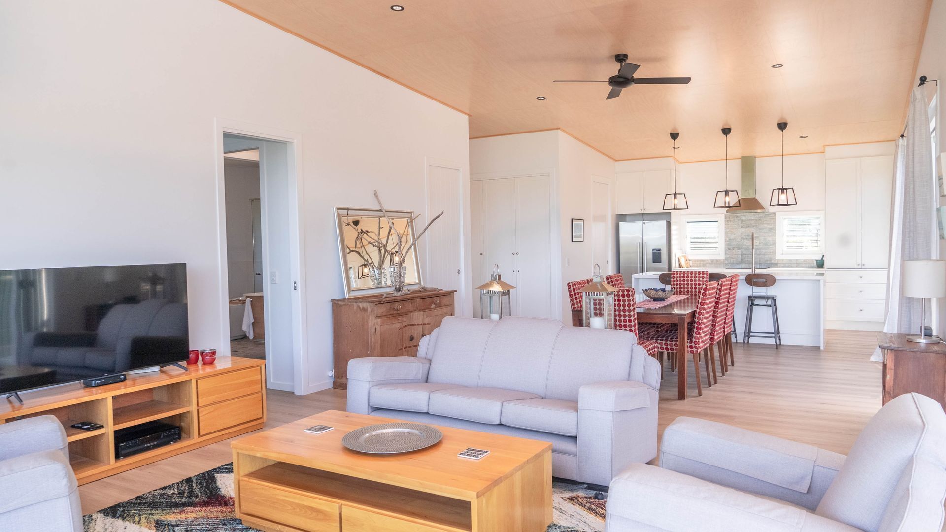 A modern living room with a flat-screen TV, a wooden coffee table, and a sofa.