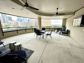 A spacious balcony with a city view, ceiling fans, and outdoor seating. - Downtown Houston Skyline Stay, Steps to Daikin Park B (Houston)