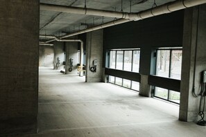 A spacious indoor area with concrete pillars, large windows, and electrical outlets on the walls. - Downtown Houston Skyline Stay, Steps to Daikin Park F (Houston)