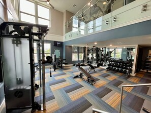 A gym with various exercise equipment, a patterned floor, and large windows. - Downtown Houston Skyline Stay, Steps to Daikin Park F (Houston)