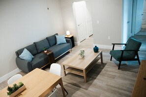 A living room with a sofa, a coffee table, a chair, and a small side table with a lamp. - Downtown Houston Skyline Stay, Steps to Daikin Park C (Houston)