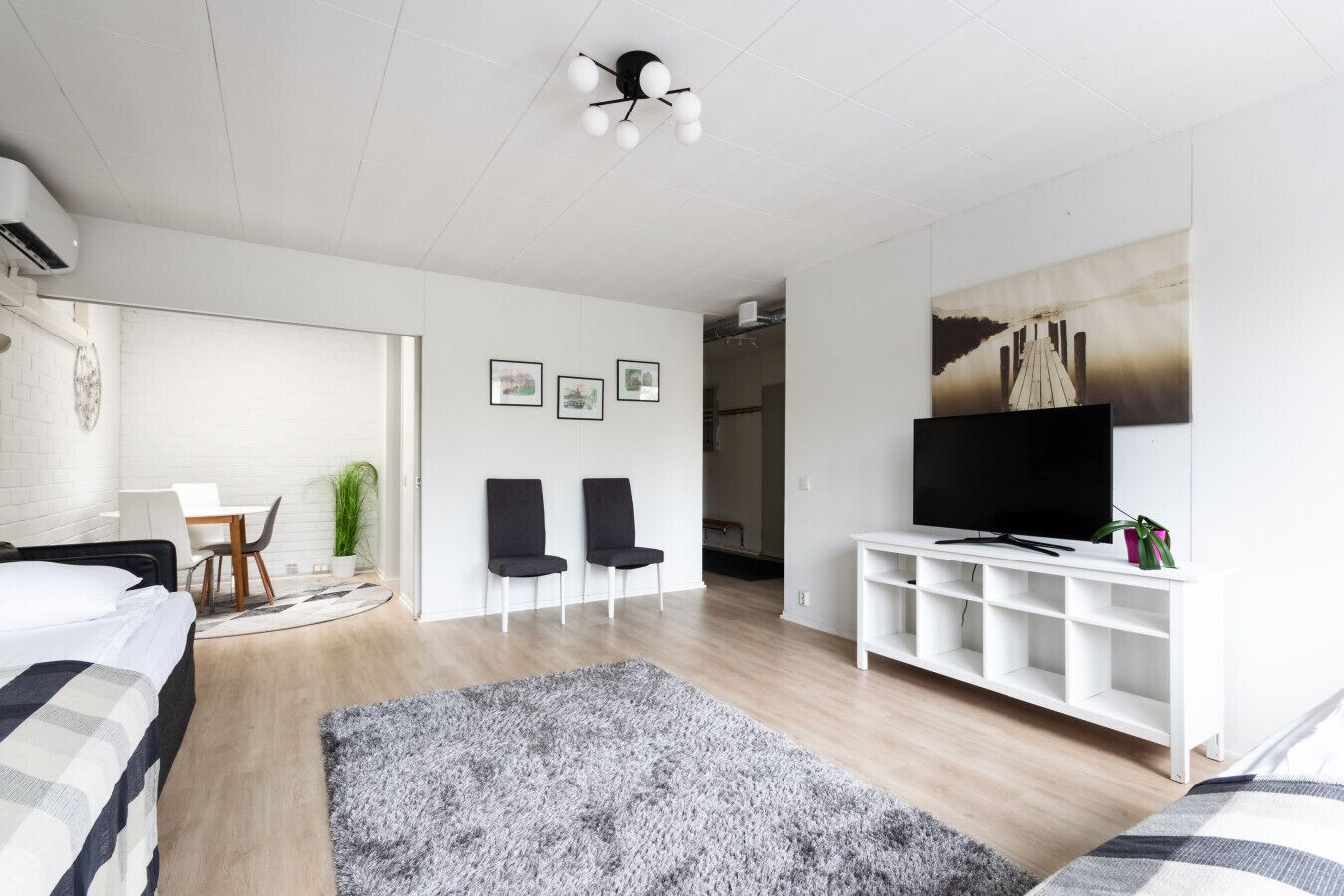 Una camera da letto moderna con un letto, una TV, una consolle bianca e un'ampia finestra.