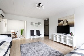 Een moderne slaapkamer met een bed, een televisie, een witte console tafel en een groot raam.