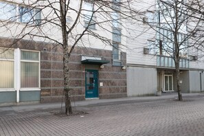 A building with a blue door, a brick facade, and a window with a metal grate. - 3 bedroom family apartment with sauna and parking (Helsinki)
