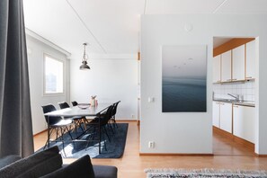 Un intérieur moderne comprenant un coin repas, une cuisine et un grand tableau représentant des oiseaux.