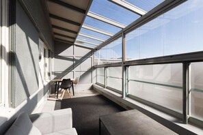 A modern interior with a glass ceiling, a table with chairs, and a view of the sky. - 3 bedroom family apartment with sauna and parking (Helsinki)