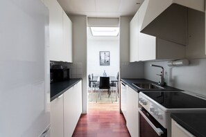 A modern kitchen with white cabinets, a black countertop, and a stainless steel sink.