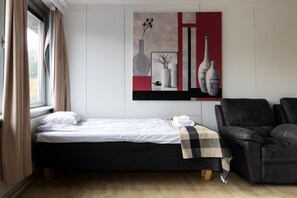 A bedroom with a bed, a black leather sofa, and a wall with abstract art. - Spacious and cozy 2 bedroom apartment for 7 (Vantaa)