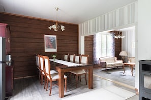 A dining area with a wooden table and chairs, a chandelier, and a sofa with a lamp. - Historic countryside schoolhouse for gatherings, retreats & celebrations (Hartola)