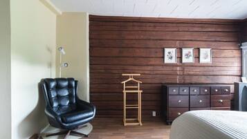 A room with a black leather chair, a wooden dresser, and a bed.
