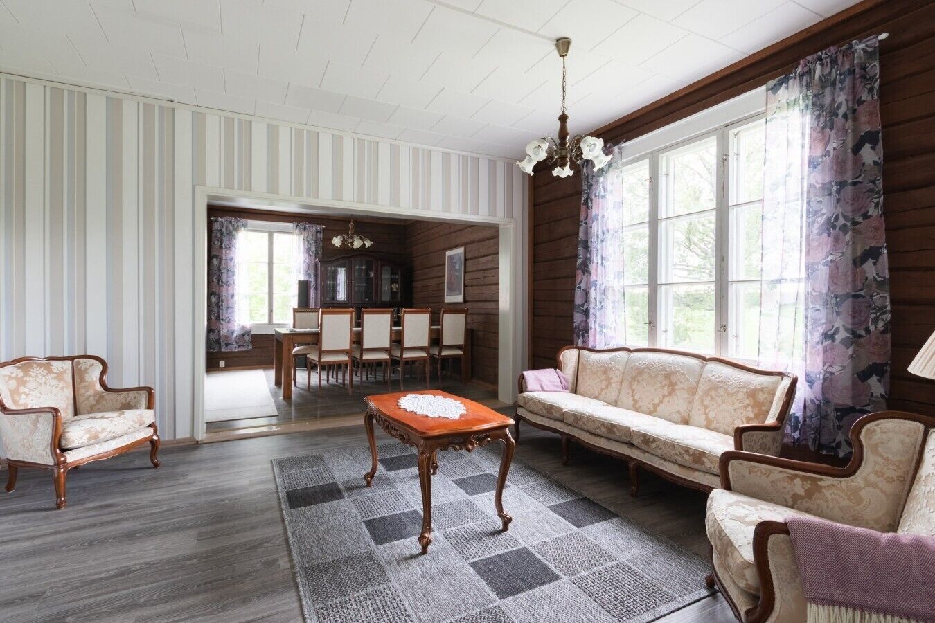 A room with a sofa, chairs, a table, and a chandelier.