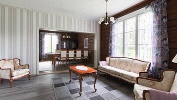 A room with a sofa, chairs, a table, and a chandelier.