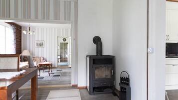 A room with a fireplace, a dining table, and a view of a hallway.