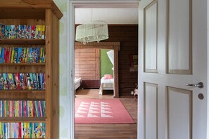 A room with a bed, a wooden bookshelf, and a red rug.