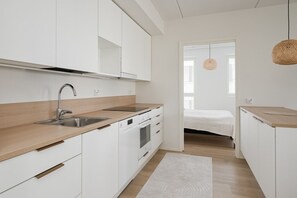 A modern kitchen with white cabinetry, a stainless steel sink, and a wooden countertop. - Family apartment with great views of Jyväskylä city (Jyväskylä)