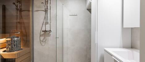 A modern bathroom with a glass shower enclosure, a wooden vanity, and a white sink.