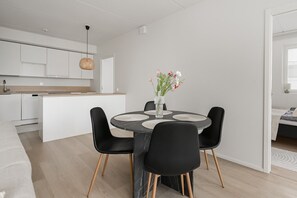 A modern kitchen with white cabinets, a black countertop, and a hanging light fixture. - Family apartment with great views of Jyväskylä city (Jyväskylä)