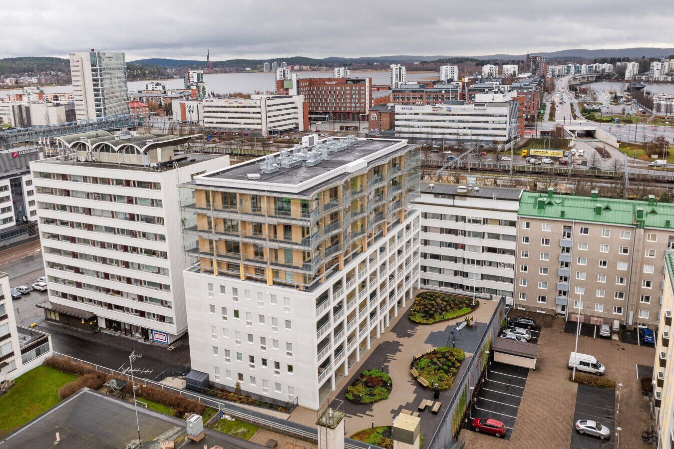 A multi-story building with a central courtyard, surrounded by other buildings, and a view of a river and hills in the background.