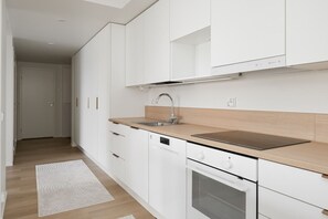 A modern kitchen with white cabinetry, a stainless steel sink, and a built-in oven. - Family apartment with great views of Jyväskylä city (Jyväskylä)