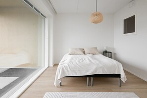 A modern bedroom with a large window, a bed with white bedding, a hanging light fixture, and a small bedside table. - Family apartment with great views of Jyväskylä city (Jyväskylä)