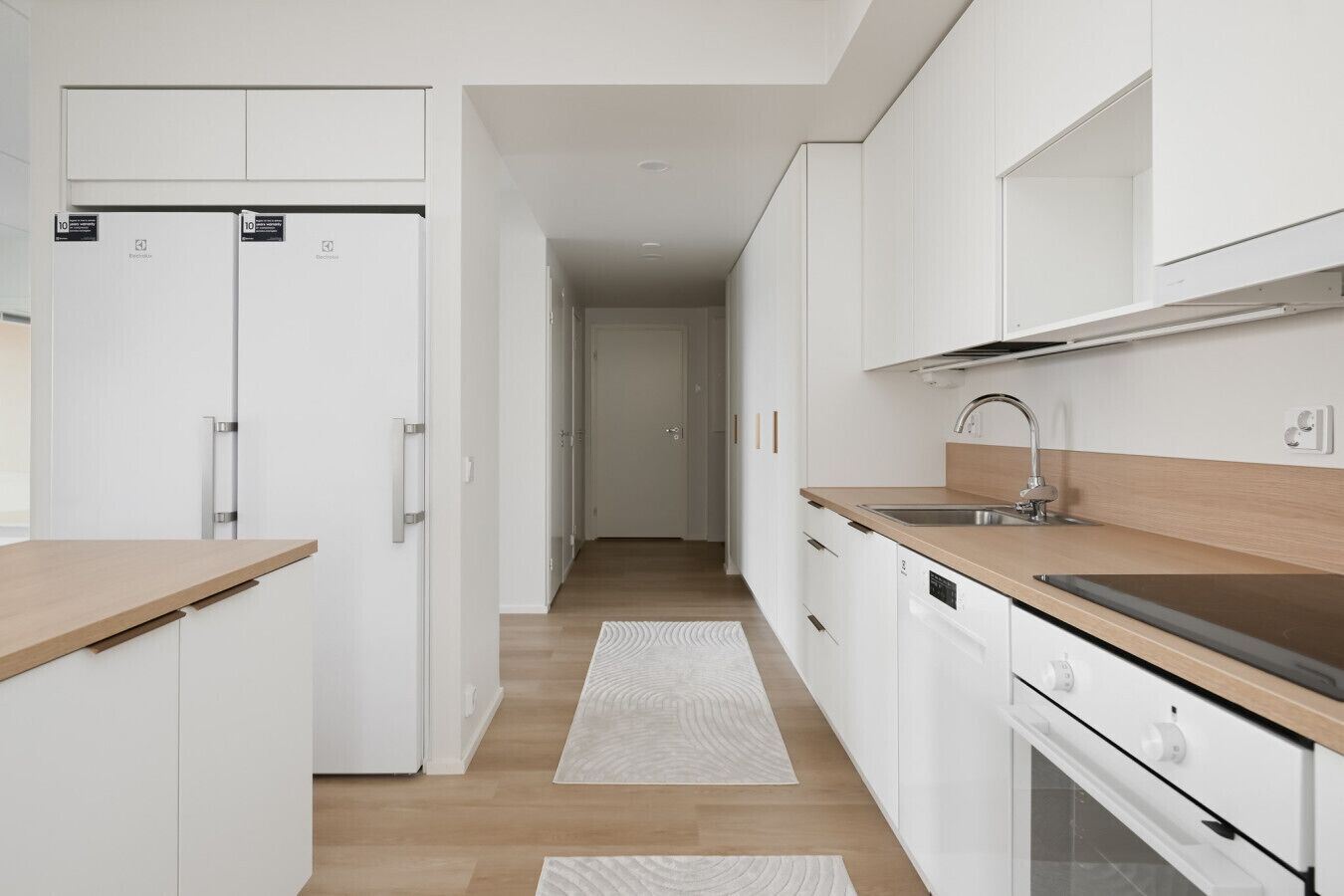 Una cocina moderna con armarios blancos, encimera de madera y pileta de acero inoxidable.