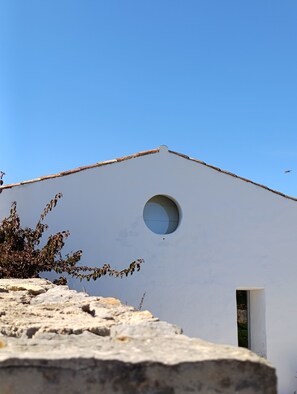 A building with a white facade, a circular window, and a small door.