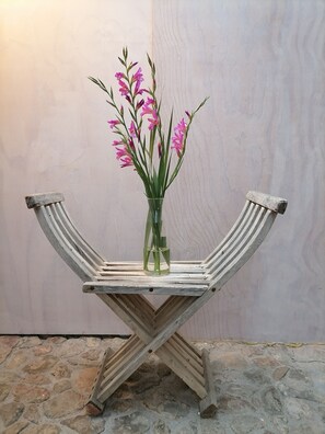 A wooden table with a glass vase containing pink flowers.