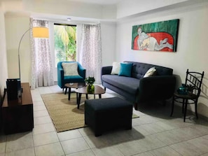 A living room with a sofa, armchair, coffee table, and a painting on the wall.