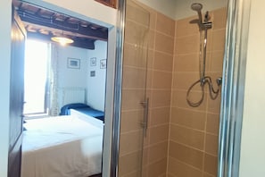 A hotel room with a bed, a shower, and a view of the room's interior. - Grandma Isola's House (Prata)